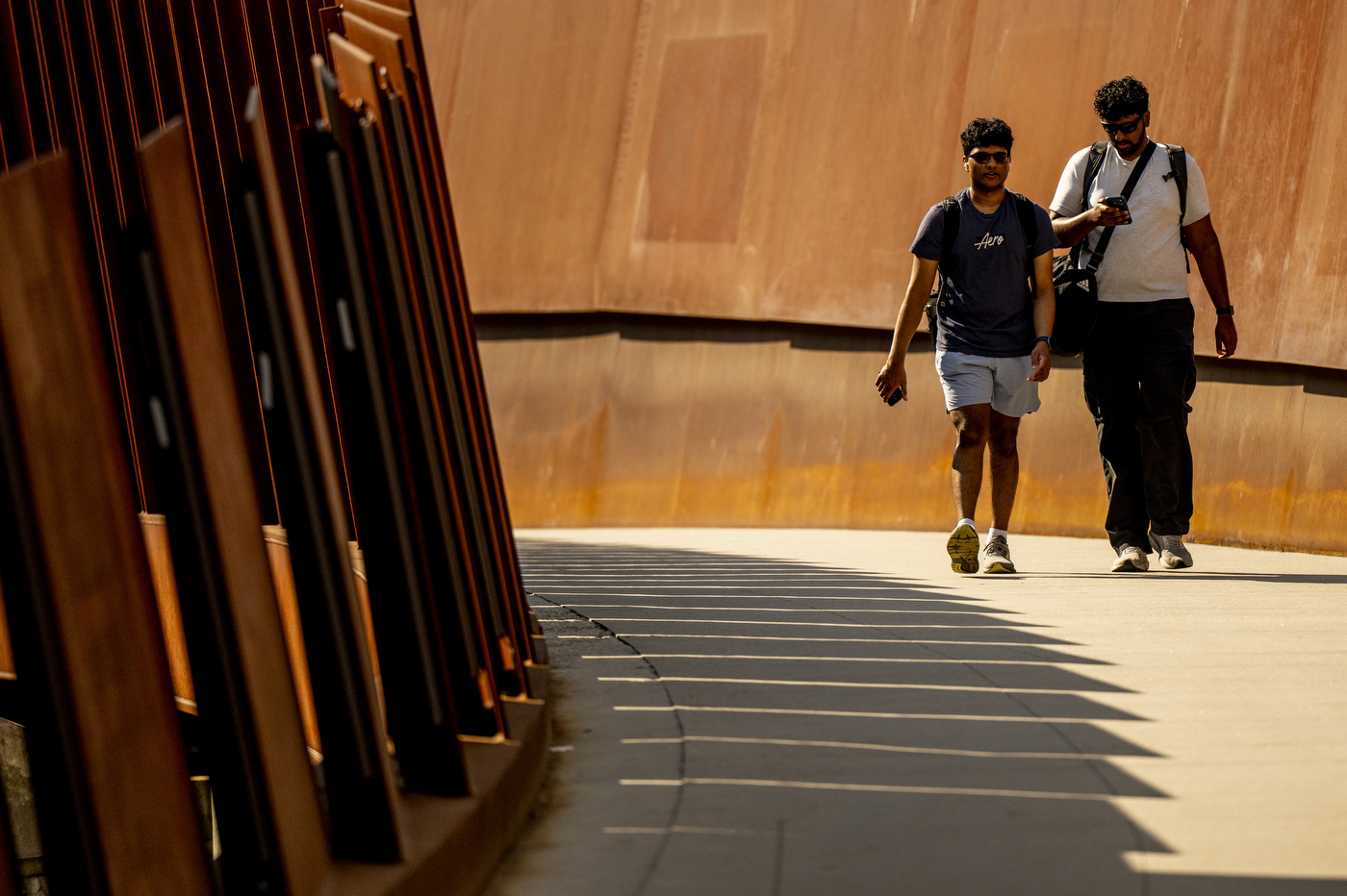 Two people walk across the pedestrian bridge.