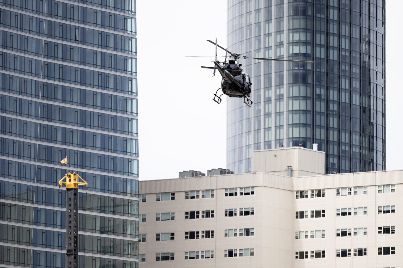 A helicopter flies low above campus with buildings in the background.