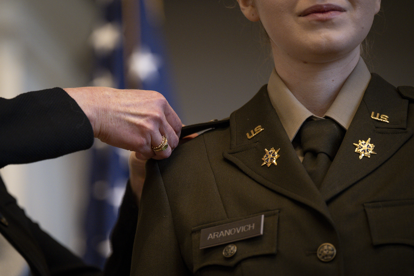 A close up of a person making adjustments and adding to the shoulder of an ROTC member's uniform.