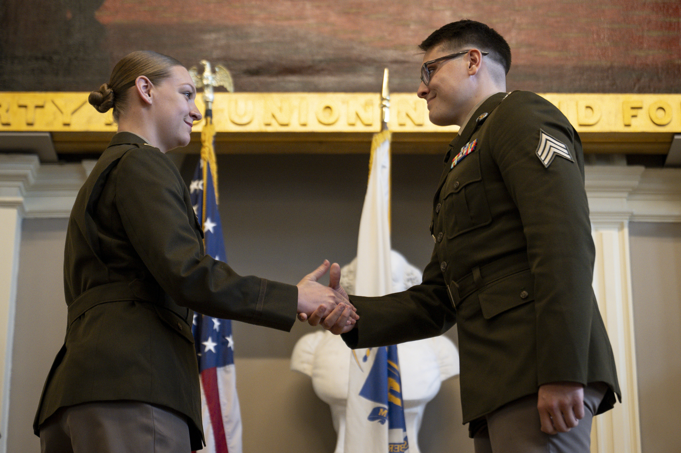 Two uniformed ROTC members shake hands.