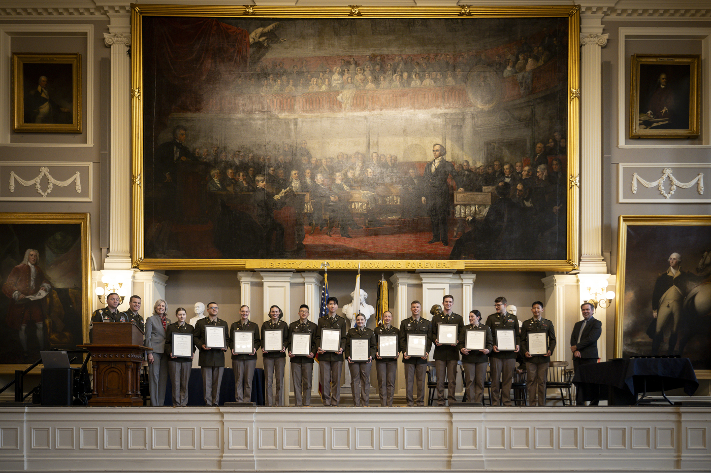 A wide shot of the Liberty Battalion posing for a photo beneath a large oil painting.