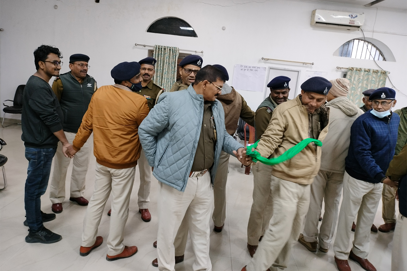 Police officers participating in a hands-on training exercise, passing a green ribbon between them in a chain.