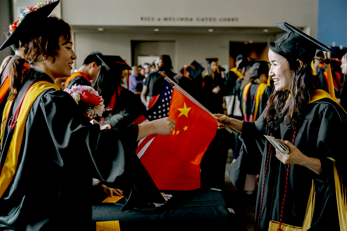 Two graduates smile at one another at Northeastern Seattle's commencement ceremony.