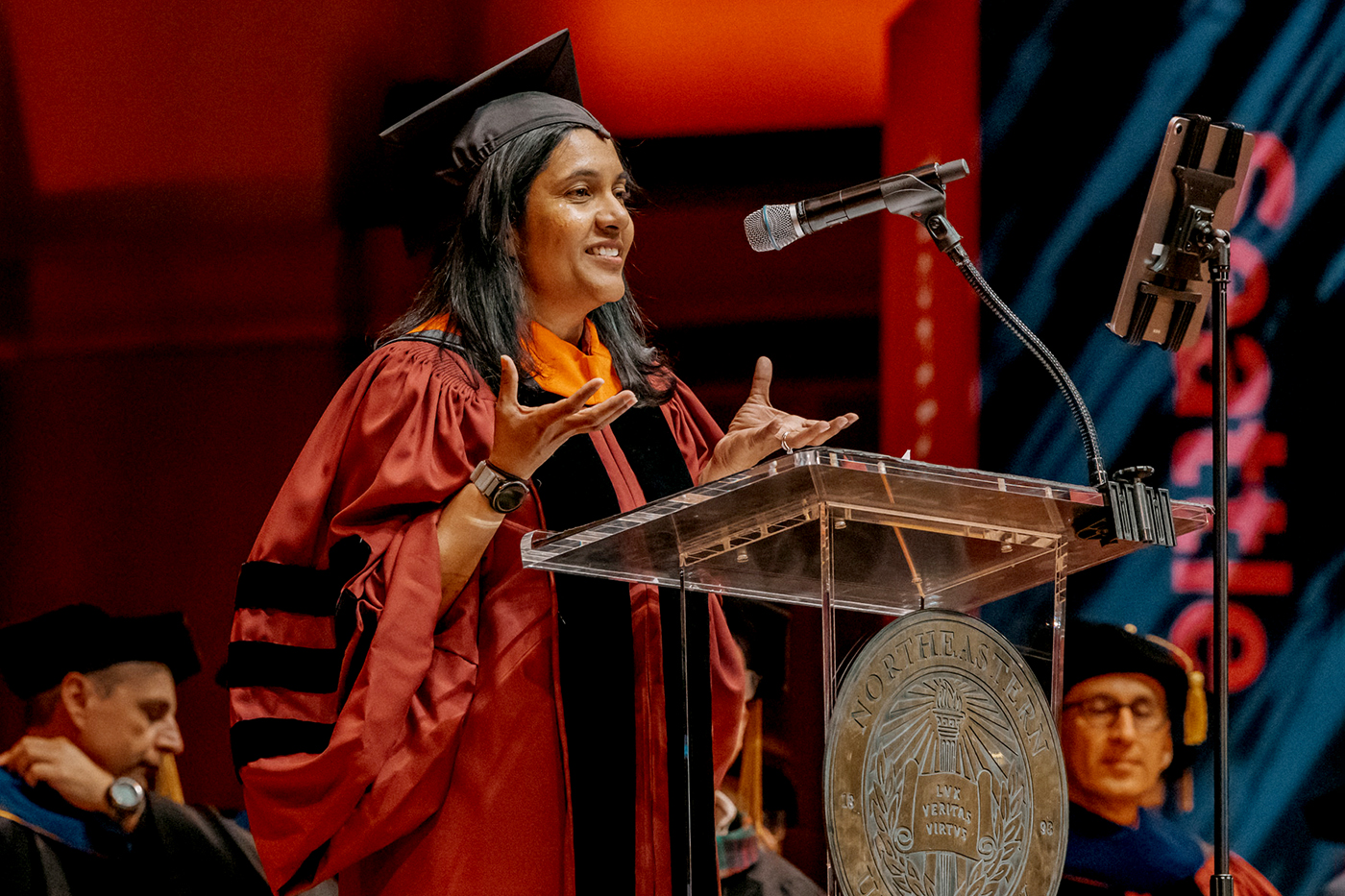 Sangeetha Visweswaran, vice president of engineering at Microsoft, stands behind a podium in a cap and robe and addresses the 2026 Northeastern Seattle graduates.