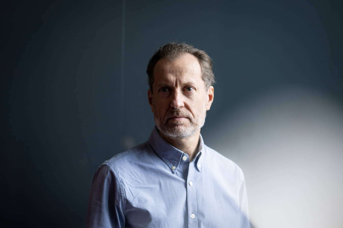Professor Lorenzo Torresani poses for a portrait in front of a deep blue-gray background.