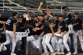The Northeastern Huskies in a celebratory posture, seen together near the dugout in black jerseys.