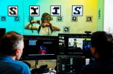 A researcher wears a VR technology headset while other researchers sitting at computers observe.