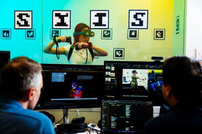 A researcher wears a VR technology headset while other researchers sitting at computers observe.