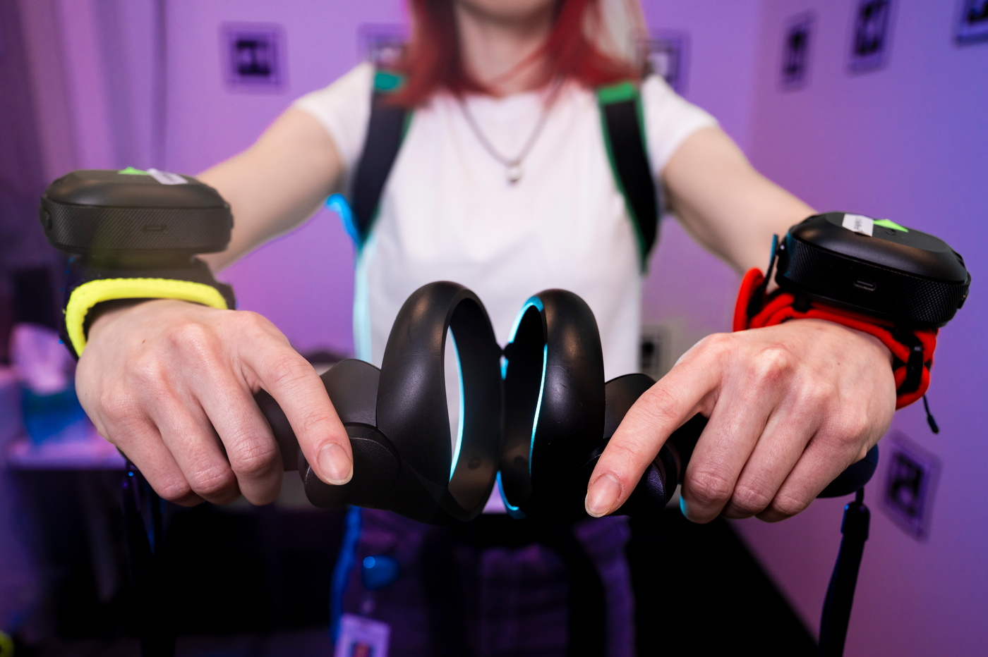 A close up a person wearing VR wrist straps and hand-held controllers.