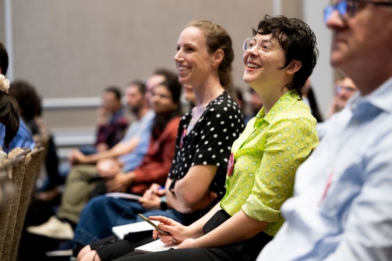 Audience members smile while listening to a physics professor during a university lecture.