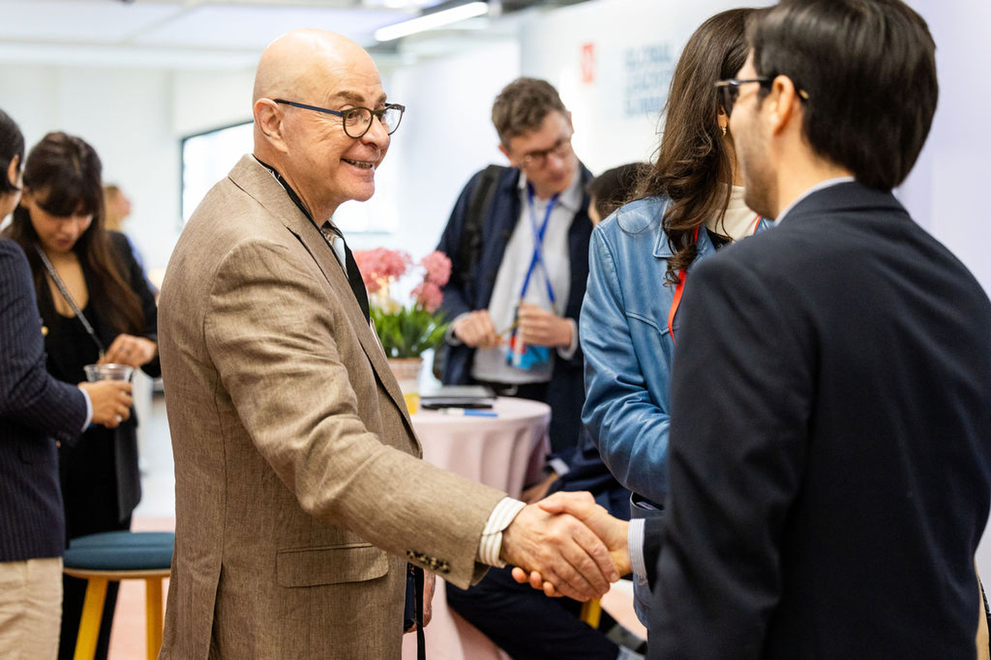 President Joseph E. Aoun shakes hands with a GLS attendee during a mixer event.