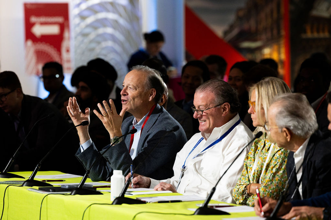 A panel of four people seated at a table, one gesturing with hands raised, during a session at the Northeastern Global Leadership Summit in London.