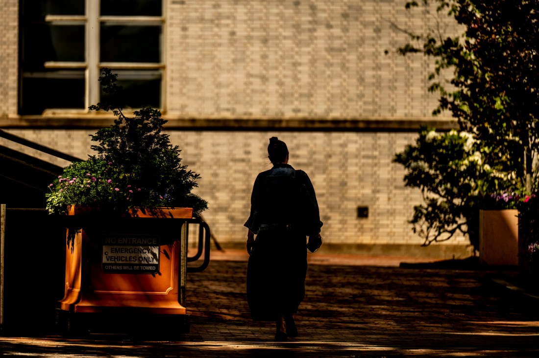 A person in shadow walks through campus.