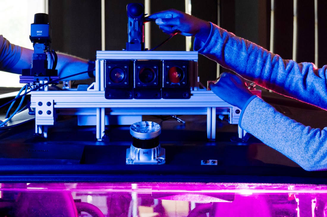 A closeup of student's hands as they work on robotics machinery.