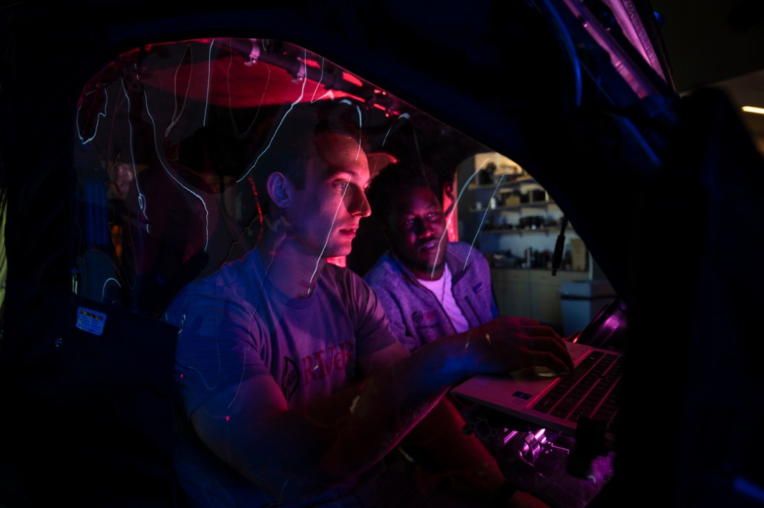 James Tukpah and Ben Cometto sit inside machinery as they work on their robotics sensor.