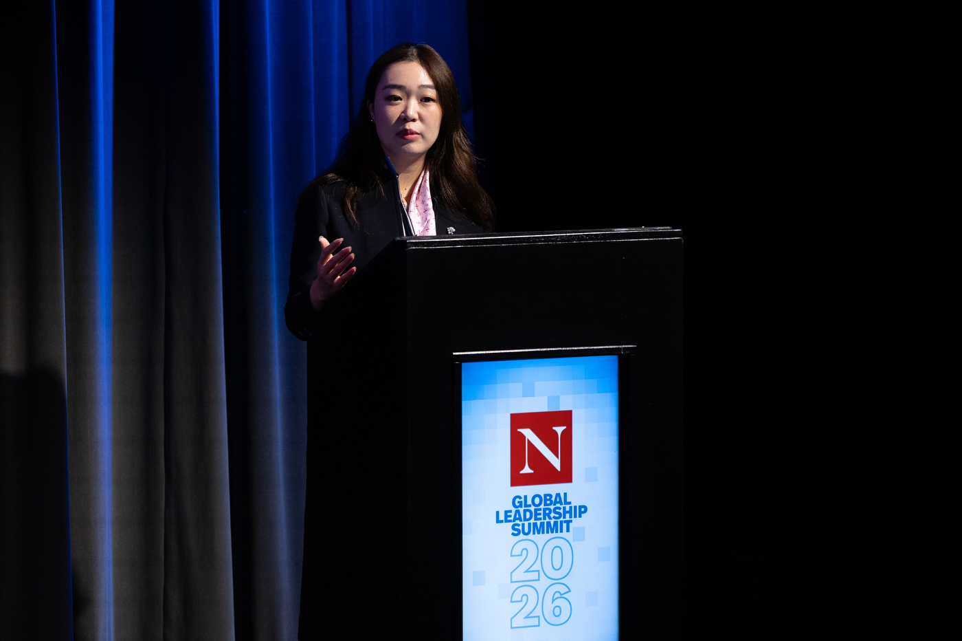 A moderator speaking at the podium during the Northeastern Global Leadership Summit in London.