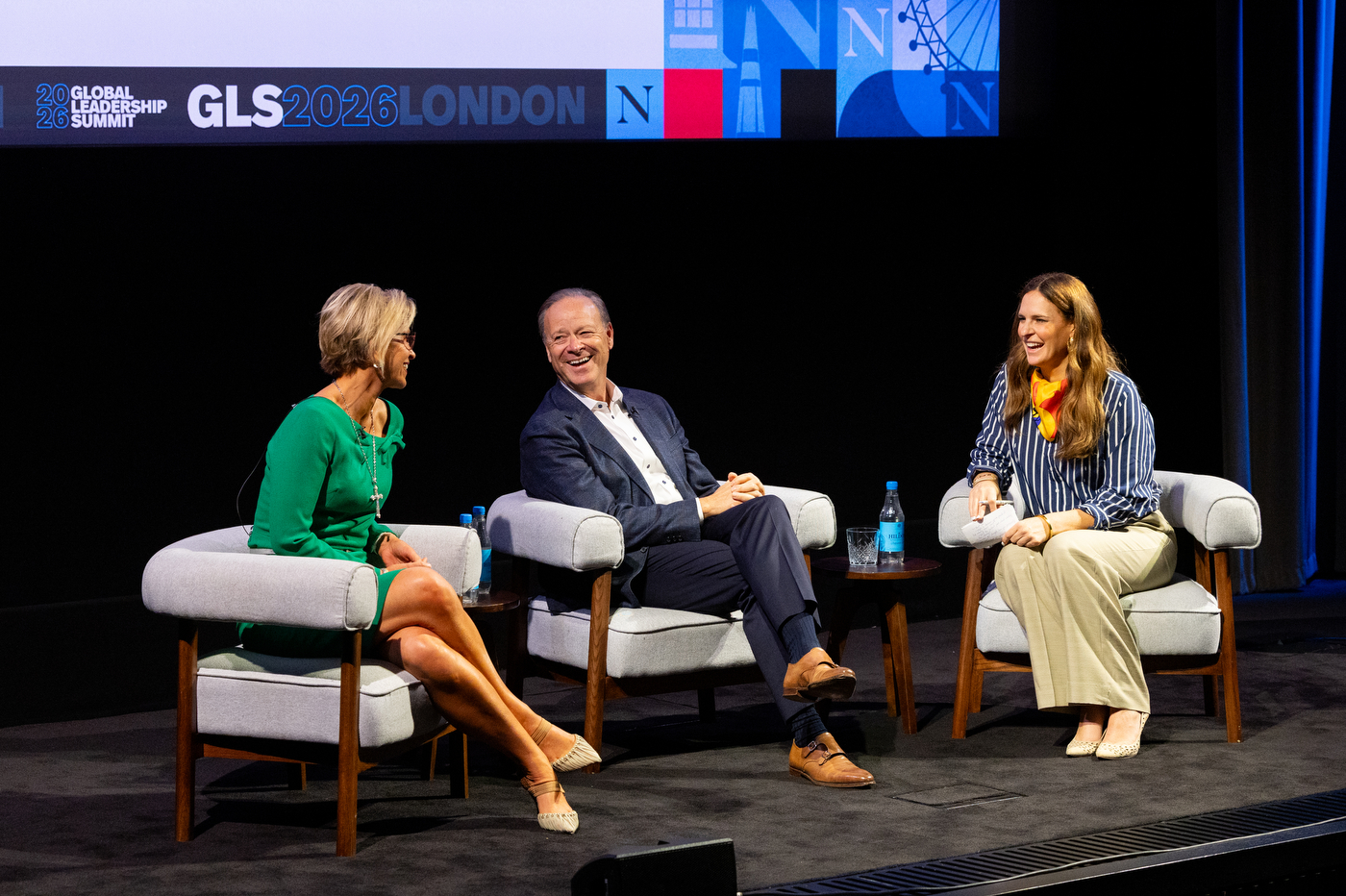 Three panelists sit on stage while talking during a GLS event.