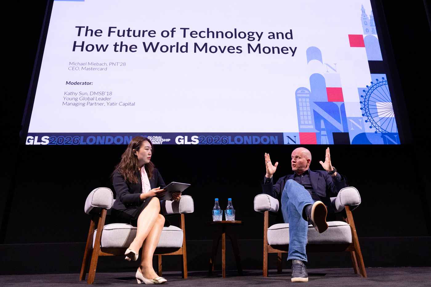 Michael Miebach and moderator Kathy Yun in conversation on stage, with a session slide titled "The Future of Technology and How the World Moves Money" visible behind them.
