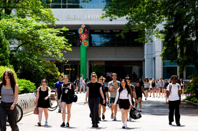 Several people walk through campus buildings.