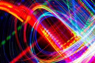 Abstract long-exposure light trails in swirling patterns of red, blue, green, and white against a black background.