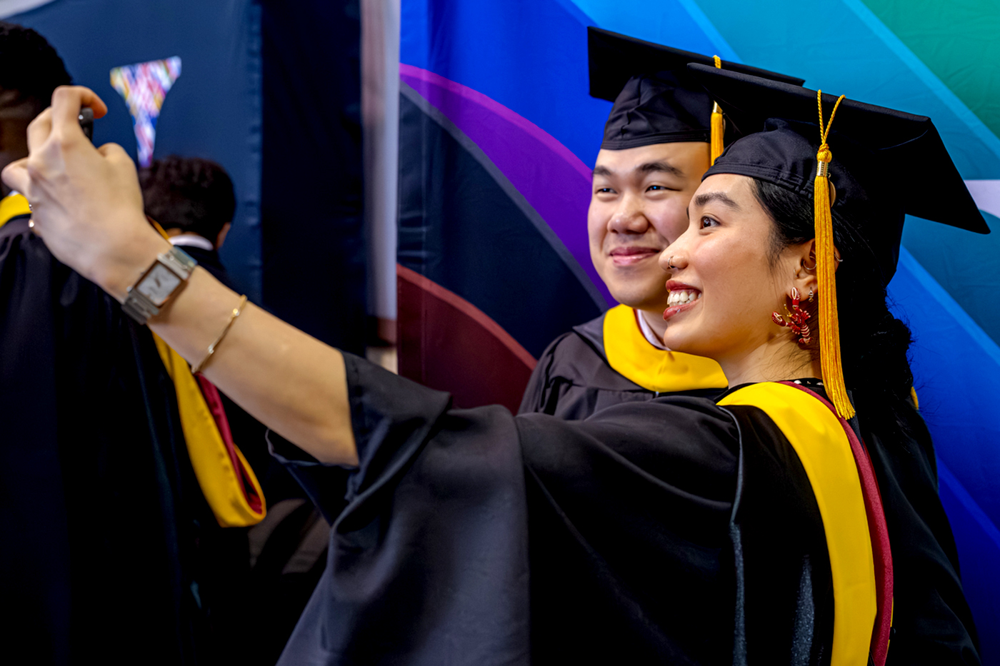 Two graduates take a selfie during a Northeastern commencement ceremony.