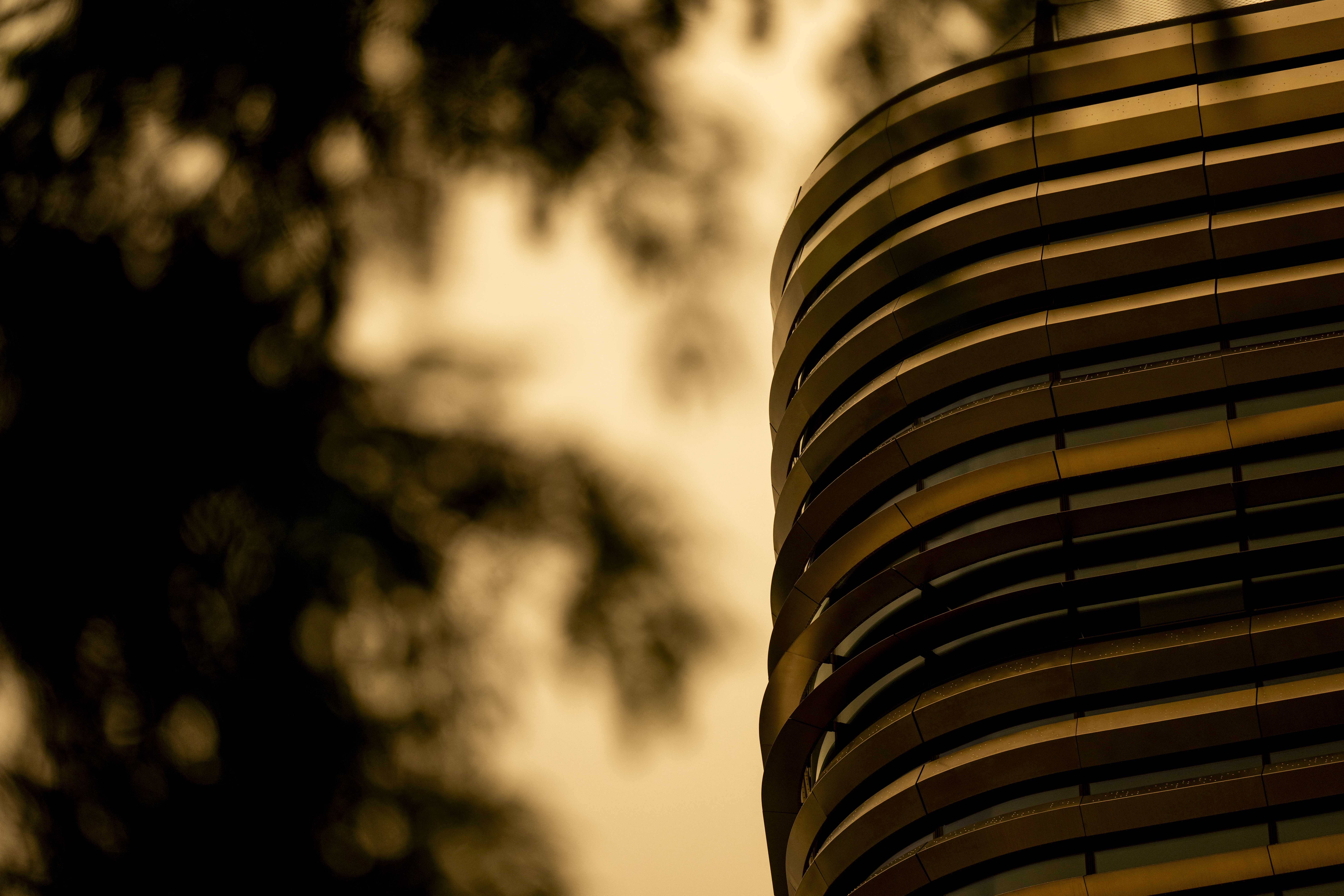 Wildfire smoke casts an orange haze over a curved glass campus building.
