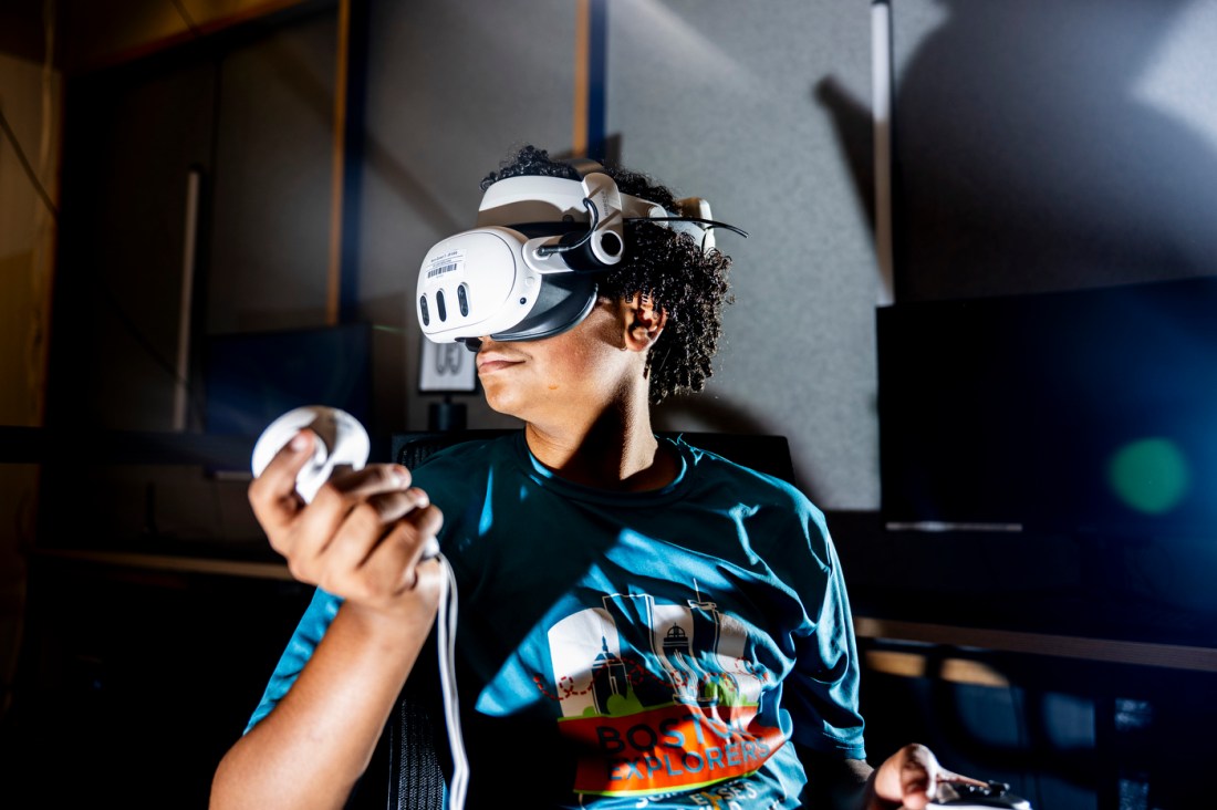 A student wears immersive VR technology headset and hand controllers.
