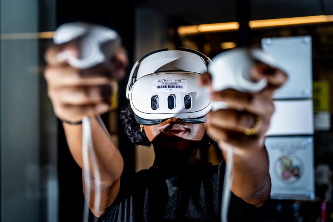 A student wears immersive VR technology headset and hand controllers.