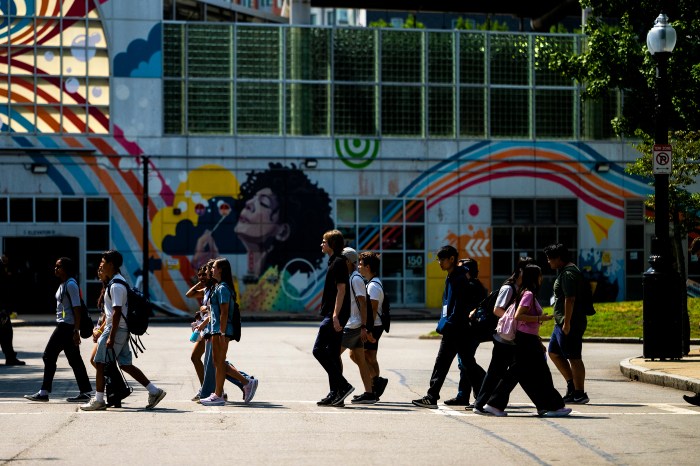 Husky101 members walk through Northeastern's Boston campus past a colorful mural.
