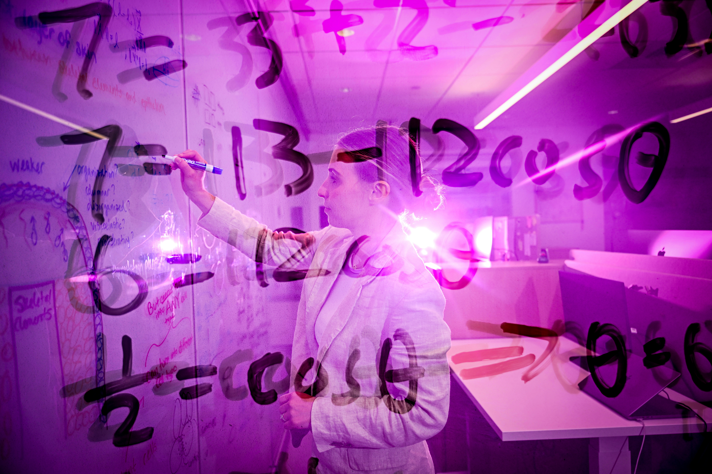 A double-exposure style photo shows a person writing numbers on a whiteboard, with overlapping numerals and a purple-lit glow creating a layered, reflective effect.