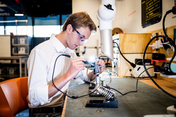 Nicolas Bejar, a mechanical engineering student and NextTile co-founder, stands at a workbench surrounded by tools and equipment in the EXP Makerspace.