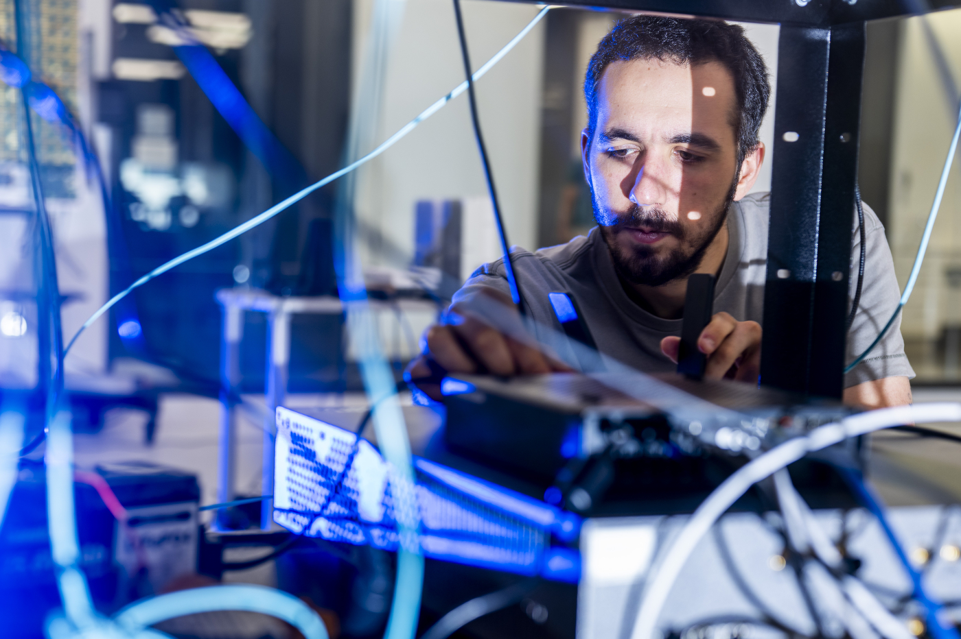 Maxime Elkael, a research scientist, examines equipment while working on 5G and AI research at Northeastern University's EXP building.