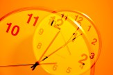 An orange-lit image of a clock superimposed over itself.