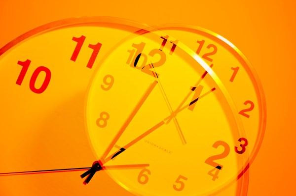 An orange-lit image of a clock superimposed over itself.