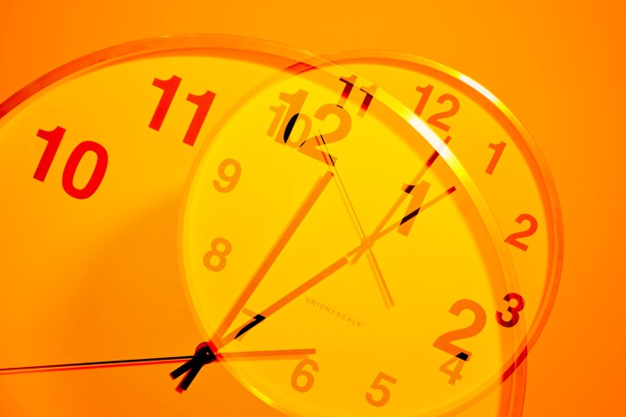 An orange-lit image of a clock superimposed over itself.
