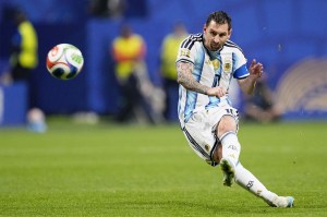 Lionel Messi mid-kick while a ball flies through the air in front of him.