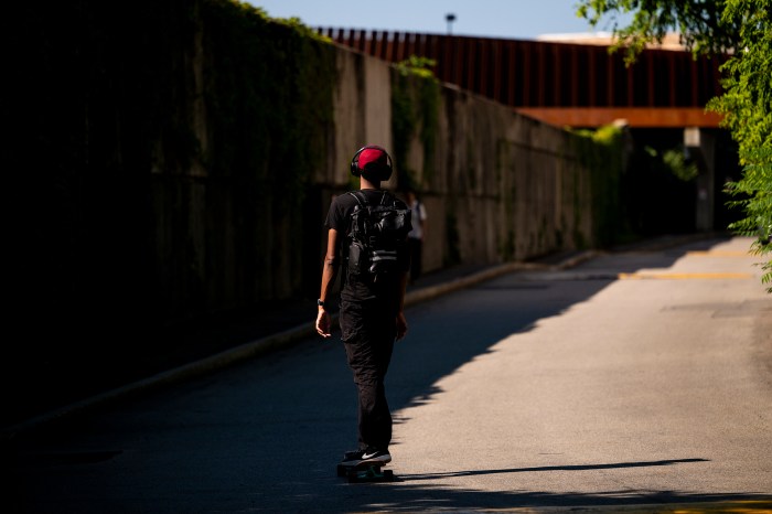 A person longboards on the pedestrian bridge.