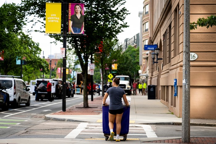 Northeastern community member moves in near a city street lined with brick buildings.