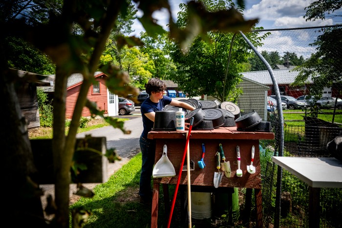 A student lives emptied plastic containers off a table outdoors.