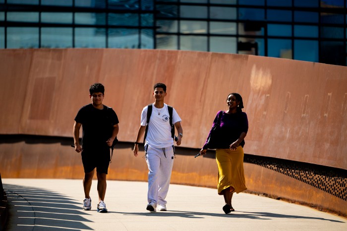 Three students walk together on the pedestrian bridge.
