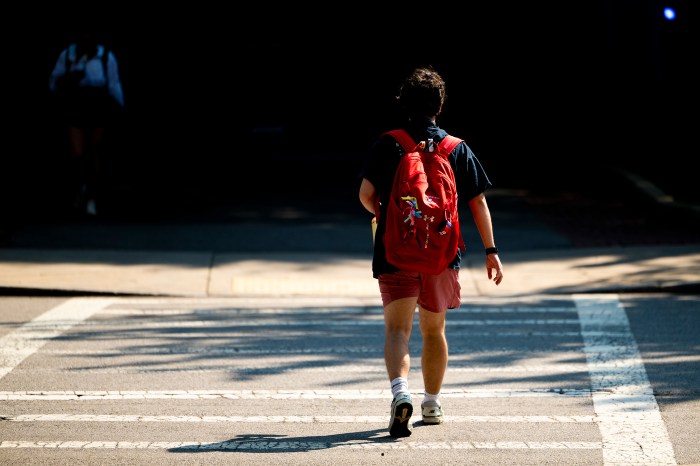 A student in a red backpack crosses the street.