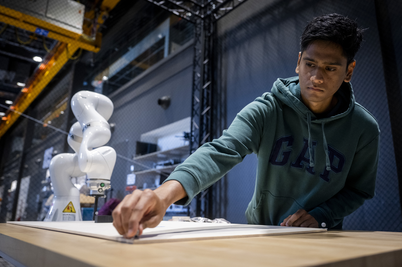 Close-up of Haroon Hublikar adjusting motion markers on the robotic arm during a dexterous manipulation test.