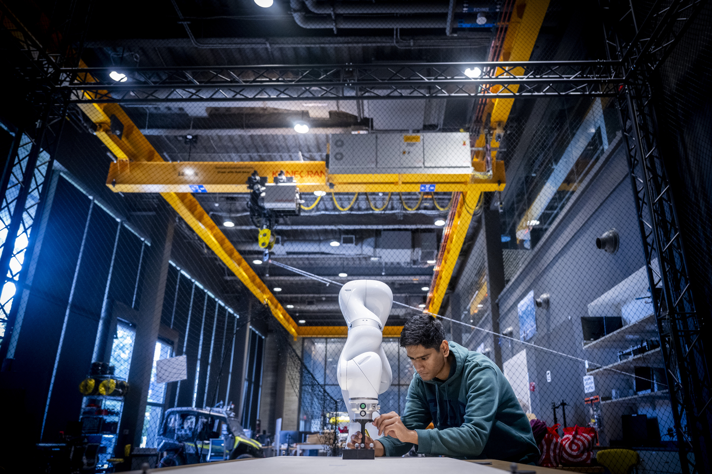 Ph.D. student Haroon Hublikar installs motion markers on a white robotic arm in the EXP robotics high bay lab.