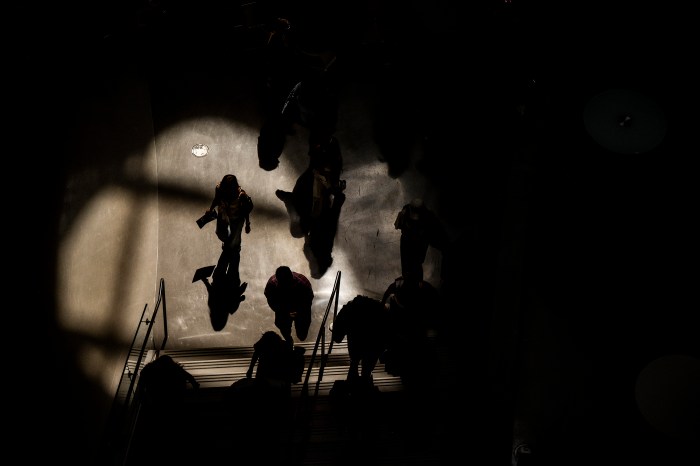Aerial view of a tour group walking through a sunlit atrium in the ISEC building, casting long shadows.