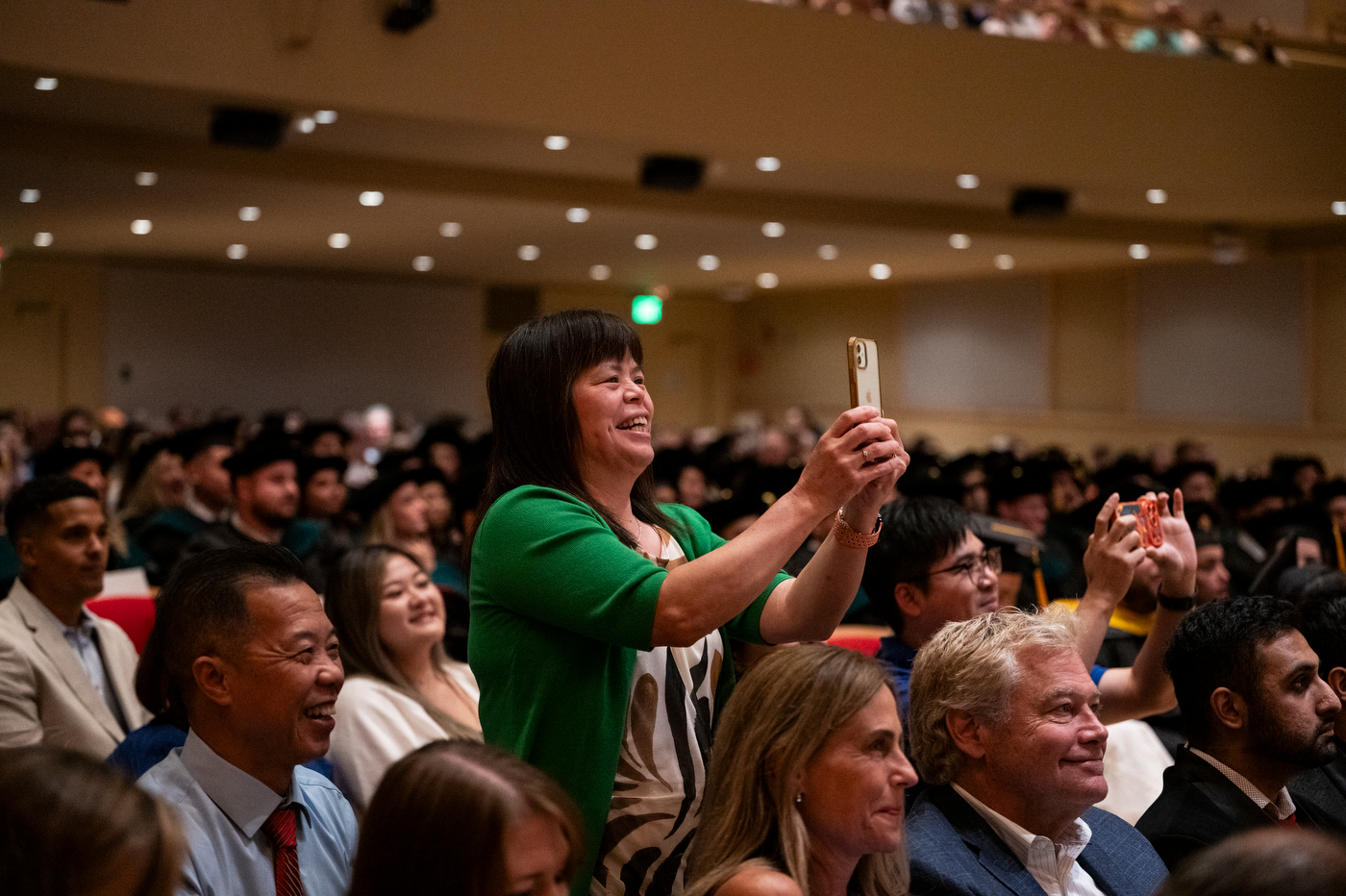 Families photograph graduates as they cross the stage at the Bouvé College Physical Therapy Graduation in Blackman Auditorium.
