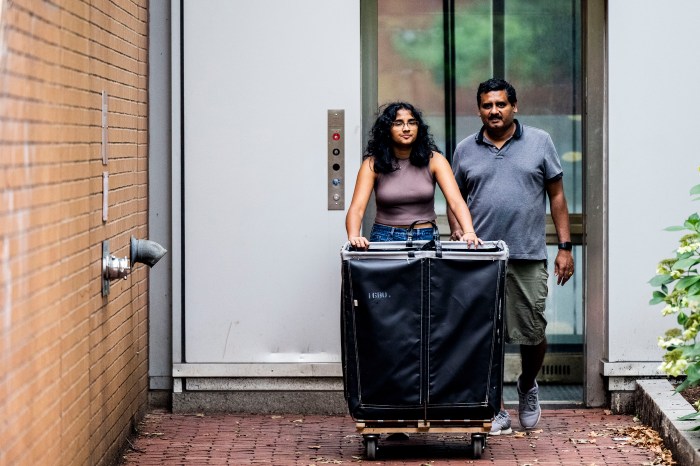Two people push a black move-in bin through a hallway at Northeastern's West Village residence hall.