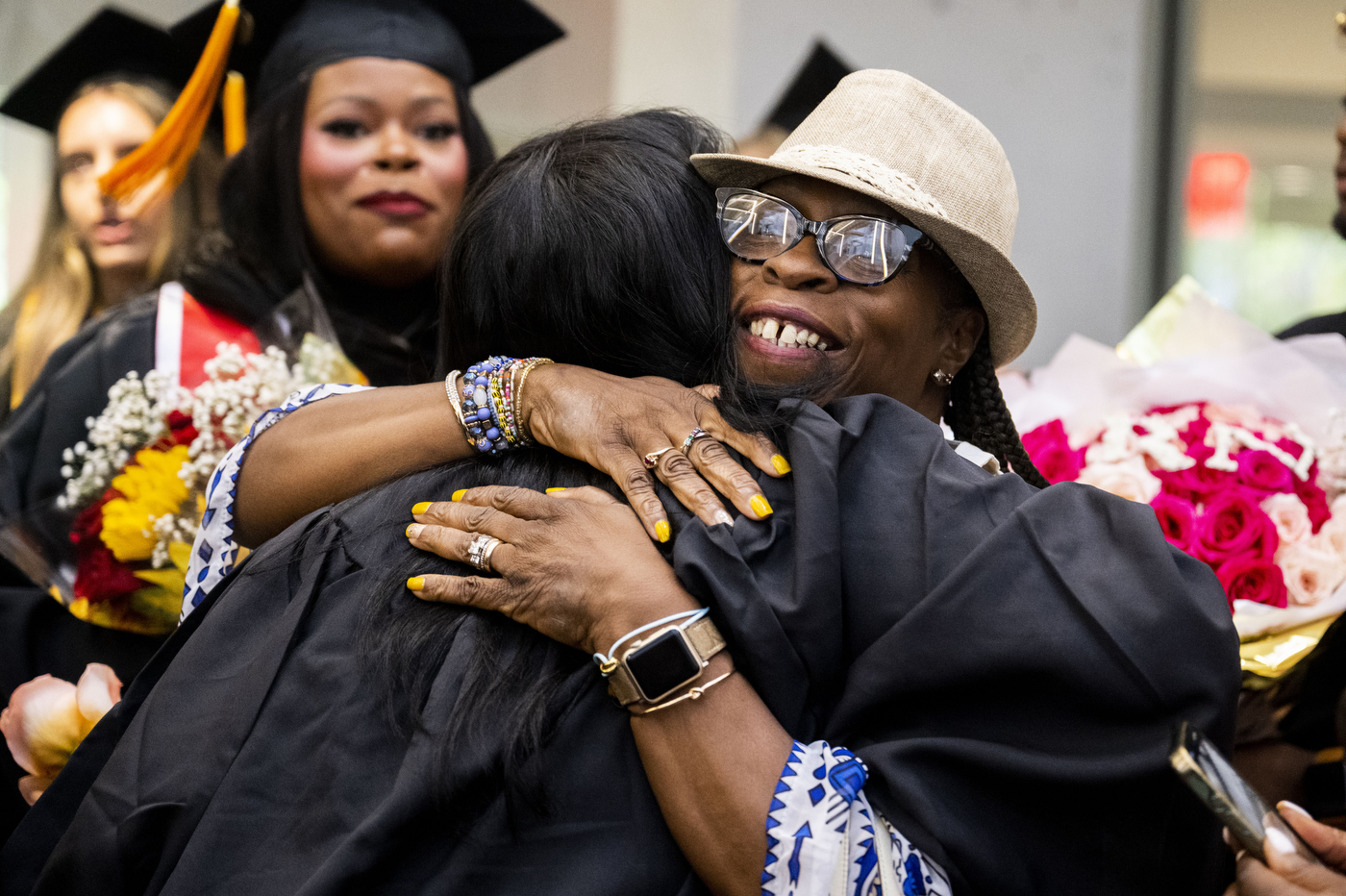 Nursing graduate embraces a family member holding flowers during the Pinning Ceremony celebration.