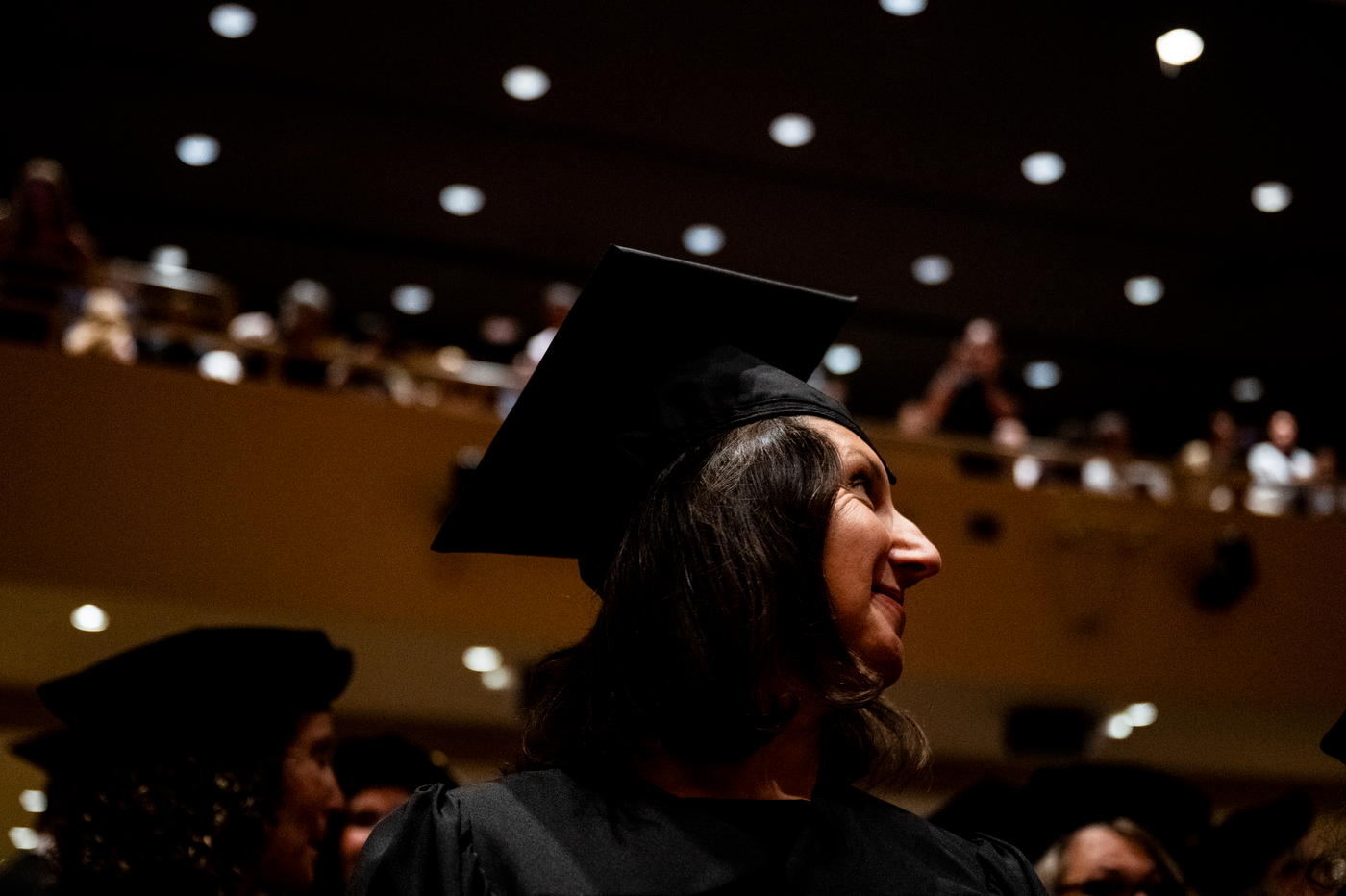 Graduate in cap and gown looks toward the stage.