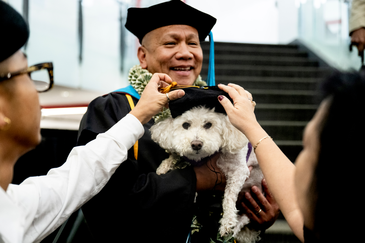 Leonard Caschiple, a College of Professional Studies doctoral graduate, smiles while holding his dog Mia, who wears a small graduation cap, after the commencement ceremony.