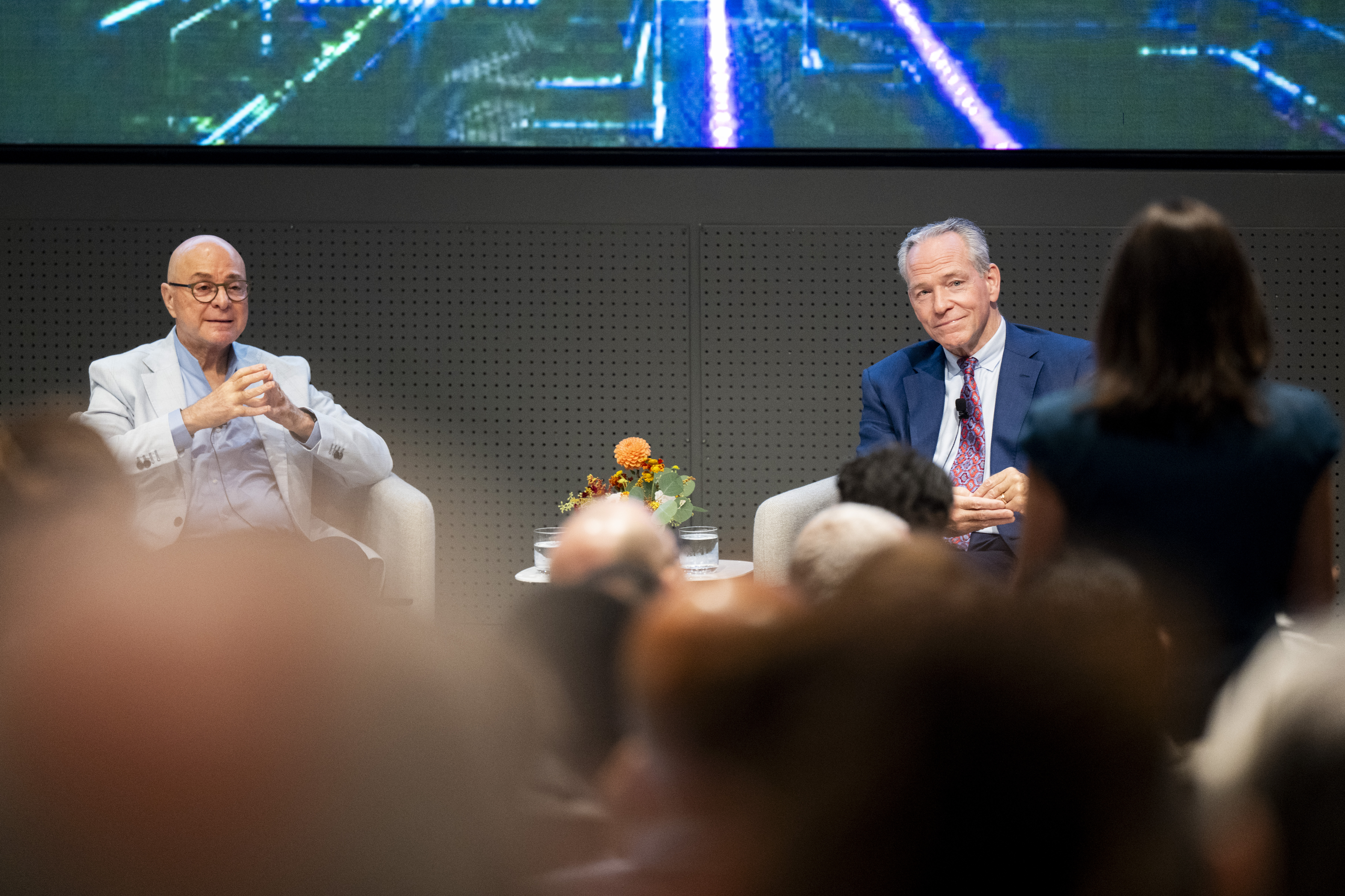 President Joseph E. Aoun and John F. Fish both listening as an audience member speaks, seen from behind in the foreground.
